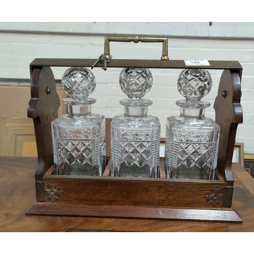 155 - A 1930's oak tantalus with three cut glass decanters and brass mountings