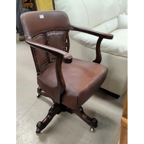 766 - An early 20th century mahogany office swivel chair in studded leaqther effect