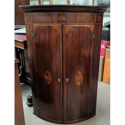 808A - A Sheraton style inlaid mahogany double door bow front corner cupboard