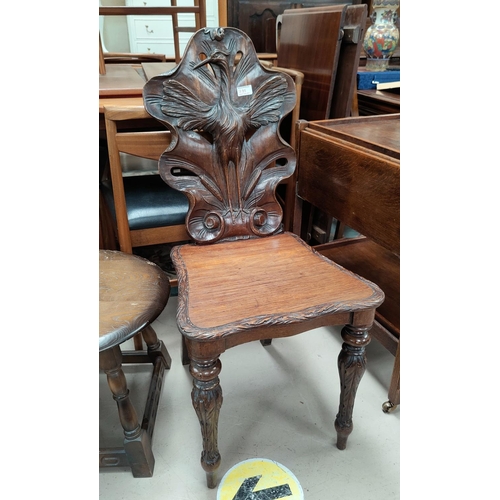 791 - An oak hall chair with finely carved back panel a naturalistic shaped back with pierced sections wit... 