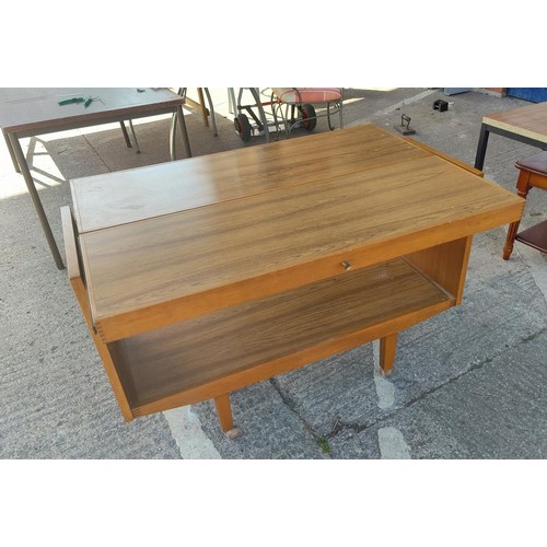 721a - A c1970's teak and veneer 2- height side table with pull up leaf, on castors