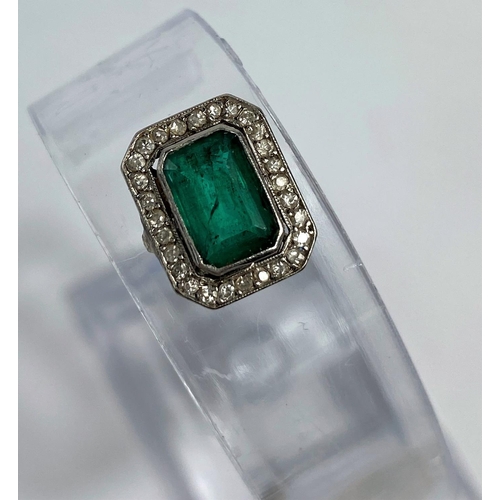 573 - A rectangular cushion cut emerald coloured stone, surrounded by small diamonds.