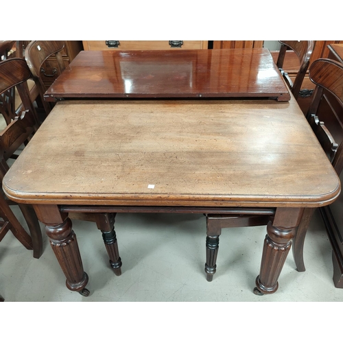 681 - A Victorian mahogany wind out dining table with one spare leaf, on reeded legs and castors