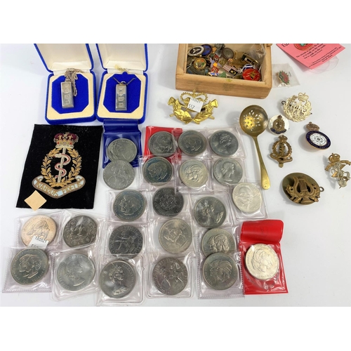 557 - Two silver ingot pendants; a selection of modern commemorative crowns; military cap and other badges