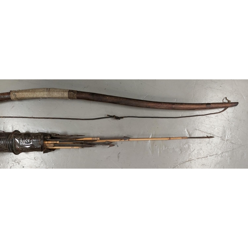 125 - A tribal bow and hide quiver with barbed arrows decoration to the quiver