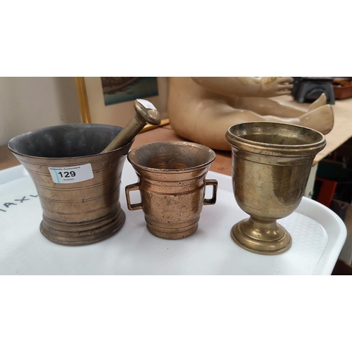 129 - Three brass antique mortars and a pestle.