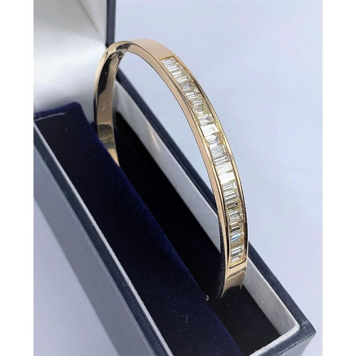 630 - A yellow metal hinged bangle, stamped 750, set with 24 baguette cut diamonds, approximate L: 2.2mm a... 