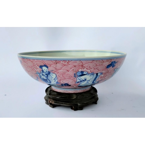 391A - A Chinese ceramic bowl decorated with blue and white figures of Sages and a red painted wave pattern... 