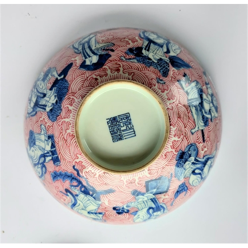 391A - A Chinese ceramic bowl decorated with blue and white figures of Sages and a red painted wave pattern... 