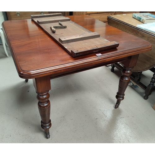 691 - A Victorian mahogany wind-out dining table on turned legs and castors, 1 spare leaf and winder, exte... 