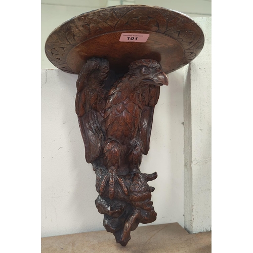 101 - A Black Forest style carved oak wall bracket in the form of an eagle, height 37cm.