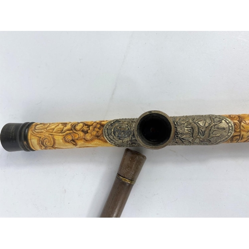 331 - A Chinese brass mounted opium pipe, 48 cm; another in carved bone, 47 cm