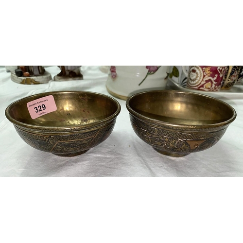 329 - A middle eastern pair of brass bowls decorated with panels of ornamental calligraphy in silver and c... 