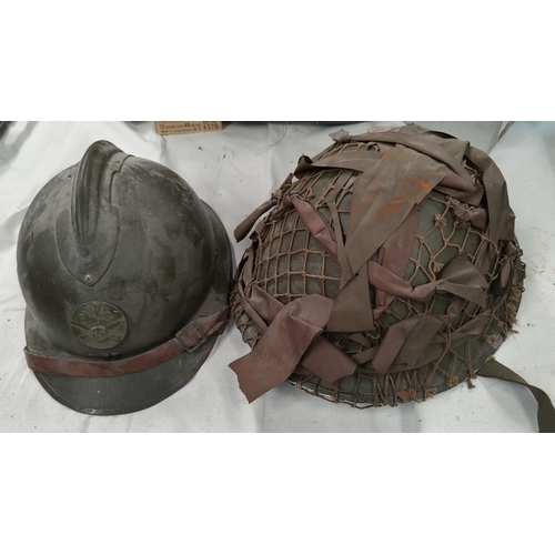 166 - A steel battle helmet with camouflage webbing and a French WWI style helmet