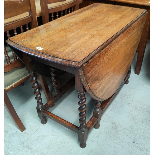 685 - A 1930's oak dining table with oval drop leaf top on barley twist gate legs