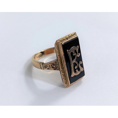 680 - A gold metal ring set with a rectangular black stone and monogram 