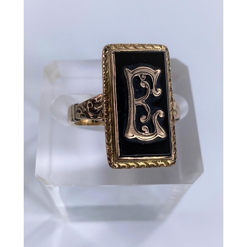 680 - A gold metal ring set with a rectangular black stone and monogram 