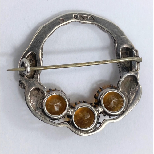 630F - A circular hallmarked silver brooch decorated with thistles in relief and set with three amber colou... 