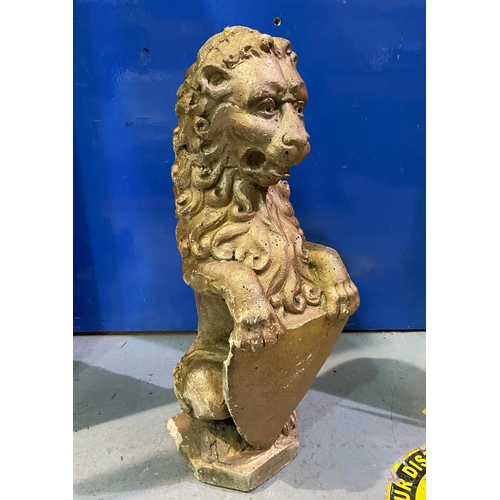 653A - A reconstituted stone garden ornament in the form of a heraldic seated lion holding a shield, in gil... 