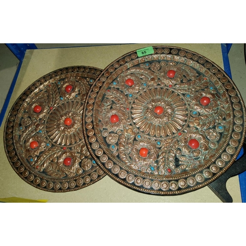 85 - A Middle Eastern pair of unusual copper wall plaques with heavily embossed and 'jewelled' decoration... 
