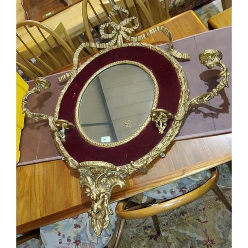 794 - An oval wall mirror in gilt frame with ornate sconces