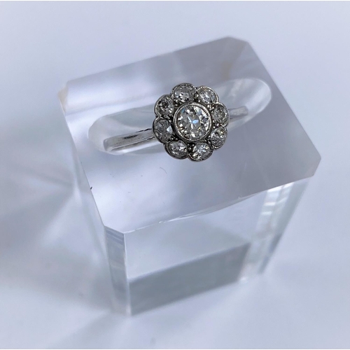 691D - An 18 carat white gold dress ring with central diamond surrounded by 8 smaller diamonds in flowerhea... 