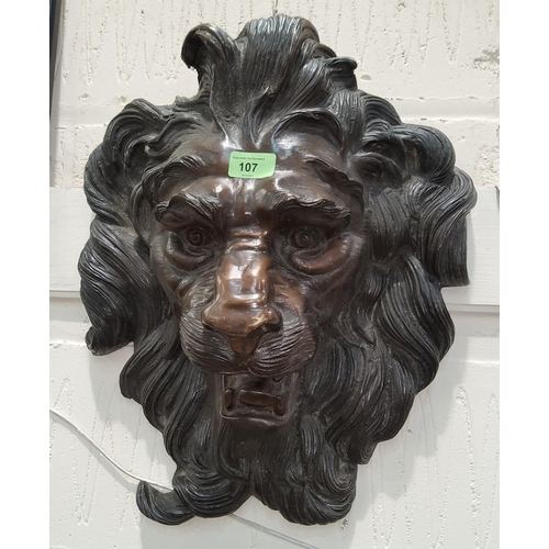 107 - A cast bronze garden wall decoration in the form of a lion's mask, steel suspension bar, 46cm