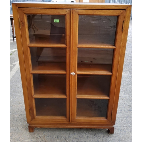 923 - A Chinese stripped wooden display cabinet/bookcase with glazed doors and arched feet