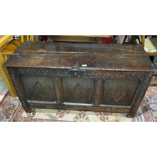 828 - A late 18th/19th century oak panelled chest with hinged plank top lid with carved decoration to the ... 