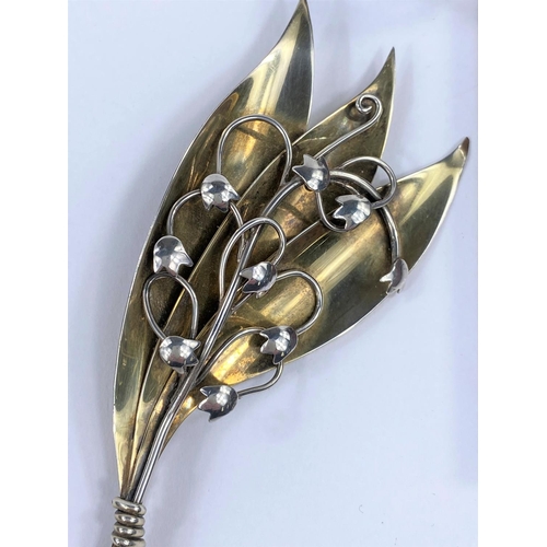 653 - A Danish silver brooch in the Georg Jensen manner with 3 elongated leaves and entwined flowers; an e... 