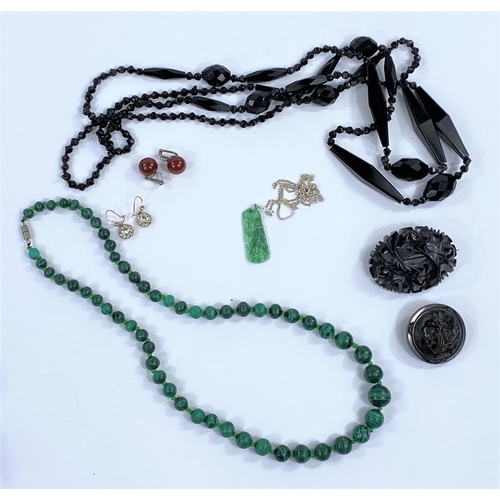 654 - A necklace of graduating malachite beads; a long French jet necklace; 2 Whitby jet brooches; a jade ... 