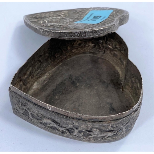 709 - An oriental white metal trinket box in the form of a heart, with extensive relief decoration, length... 