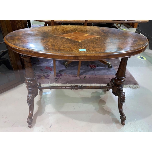 803 - A Victorian oval centre table in inlaid quarter veneered burr walnut, on turned columns and carved s... 