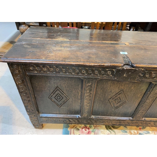 828 - A late 18th/19th century oak panelled chest with hinged plank top lid with carved decoration to the ... 