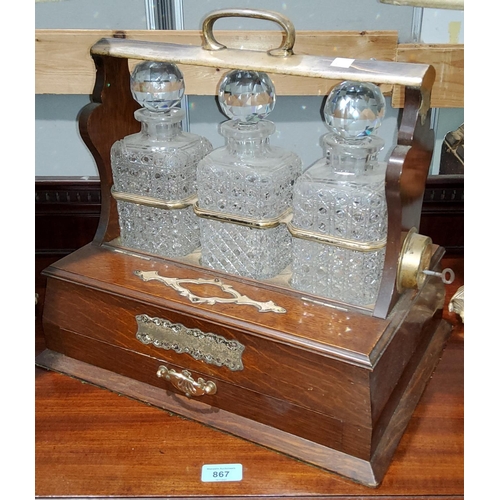 131 - An Edwardian oak and silver plate 3 bottle Tantalus with side compartments stamped for Walker & Hall... 