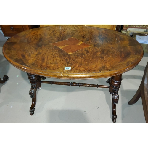 803 - A Victorian oval centre table in inlaid quarter veneered burr walnut, on turned columns and carved s... 