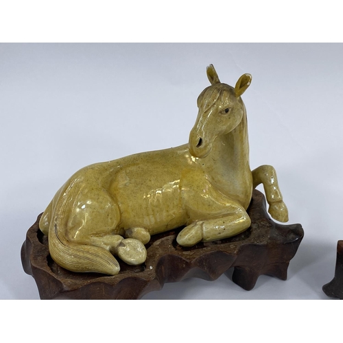 435 - A pair of Chinese yellow glaze horses lying down on
fitted wooden stands, length 18cm (some areas of... 