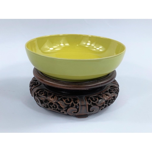 436 - A Chinese yellow glaze shallow bowl with seal mark to base, on a hardwood carved stand, diameter 15.... 