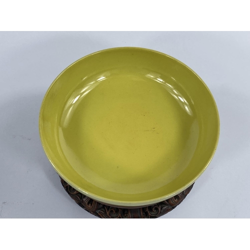 436 - A Chinese yellow glaze shallow bowl with seal mark to base, on a hardwood carved stand, diameter 15.... 
