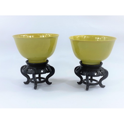 437 - A pair of Chinese yellow glaze rice bowls, on hardwood stands, with seal mark to bases, diameter 12.... 