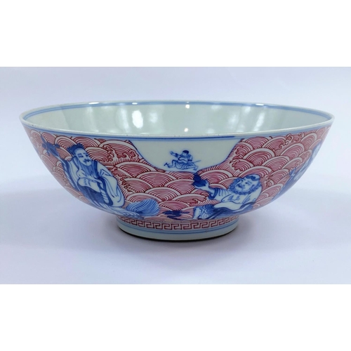 438 - A Chinese ceramic bowl with blue and white figures of sages
etc, with detailed red wave decoration t... 