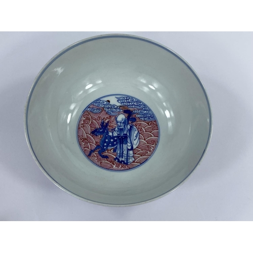 438 - A Chinese ceramic bowl with blue and white figures of sages
etc, with detailed red wave decoration t... 