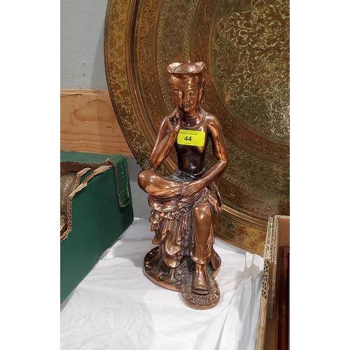 44 - A copper coloured metal Eastern figure of a man seated cross legged, height 30cm