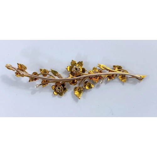 670 - A yellow metal brooch in the form of an elongated leaf and flower, set seed pearls