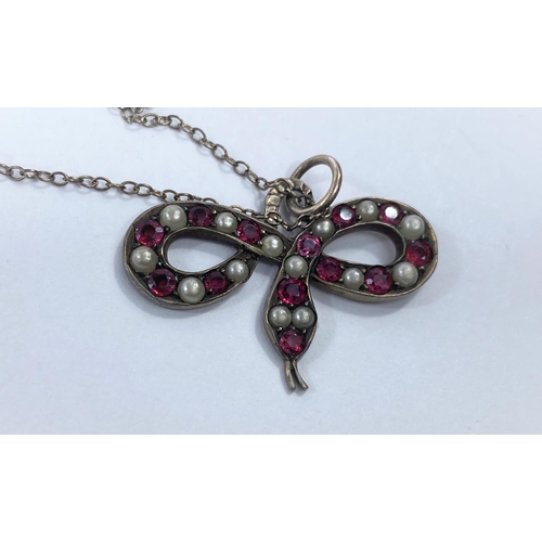 724 - A ruby coloured stone and seed pearl inset pendant in the form of snake