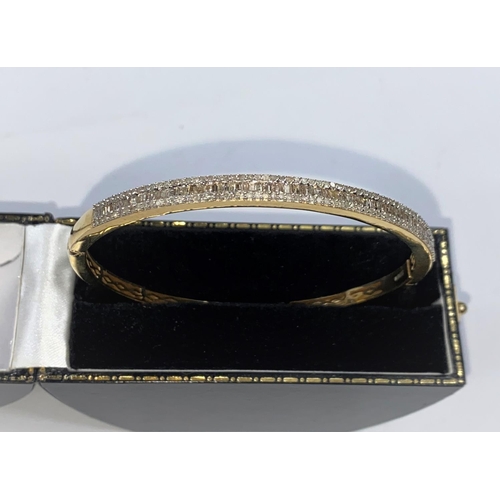 714a - An originally boxed Vermeil gold plate on silver bangle with a row of baguette cut diamonds surround... 