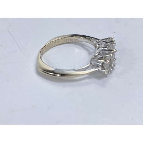 717b - An white metal lady’s dress ring, the shank stamped 18K, set with 3 groups of diamond flowerhead clu... 