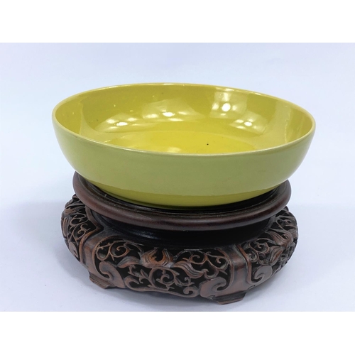 427 - A Chinese yellow glaze shallow bowl with seal mark to base, on a hardwood carved stand, diameter 15.... 