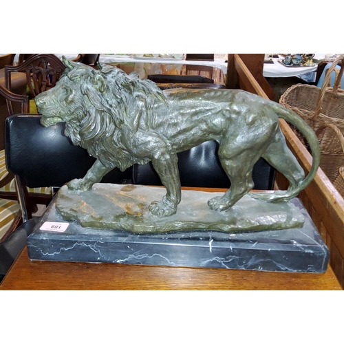 188 - A bronze of a prowling lion an a black marble base, length 43cm.