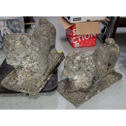 937 - A pair of reconstituted stone garden ornaments in the form of crouching lions